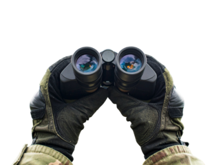 Black Binoculars Held by Explorer Against Mountain Landscape