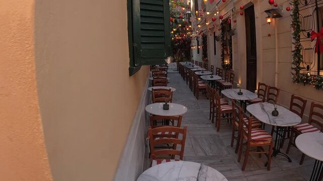 Camera pans from one wall to reveal an outdoor restaurant decorated for Christmas in Southern Europe. Holiday dining and festive atmosphere idea. Christmas lights and outdoor celebration concept.