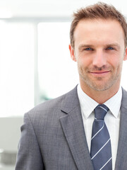 Mid adult man standing in office wearing grey suit, white shirt, blue striped tie, copy space