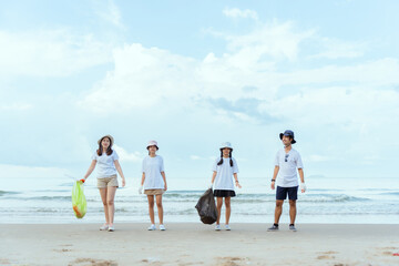 Volunteer group cleaning beach with enthusiasm while collecting trash in bags during a sunny day