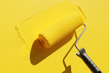 Obraz premium Paint Roller Resting on Bright Yellow Wall