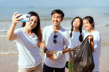 Friends enjoy a beach cleanup while taking a selfie against the ocean background on a sunny afternoon