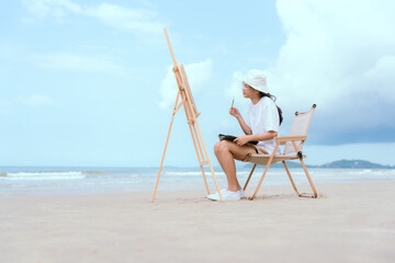 Young artist paints coastal landscape at sunny beach during daytime
