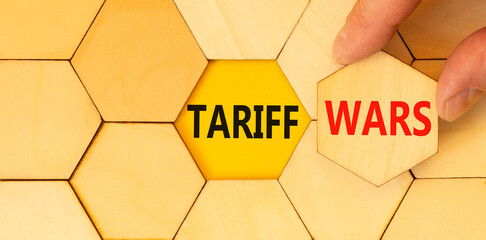 Trade tariff wars symbol. Concept word Tariff wars on beautiful wooden puzzles. Businessman's hand....