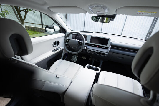 Electric car interior details adjustments. Inside car interior with front seats, driver and passenger, textile, windows, console, gear shift, electric buttons, digital speedometer, steering wheel