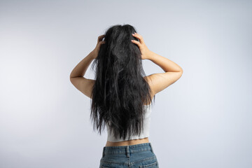 Fototapeta premium Woman with messy black hair in a white crop top and blue jeans against a white background
