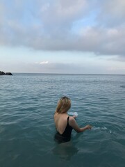 Female swimmer in turquoise sea under the morning sun.
