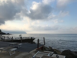 Italian coastal town with rocky waterfront at dawn.

