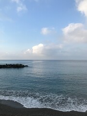Peaceful beach scene in Italy with stones and blue waves.
