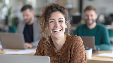 A young, cheerful businesswoman with a warm and genuine smile, working on her laptop in a collaborative office space. Her happiness and positive energy reflect a successful and healthy work culture