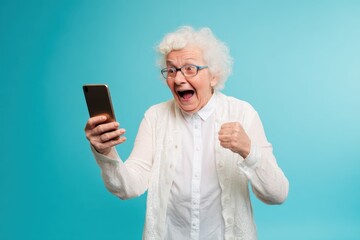 Excited senior woman looking at her smartphone, celebrating and cheering, with a big smile on her face.