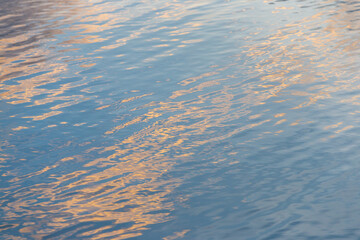 An abstract summer reflection of sun on the blue water's rippling surface creates a calm, liquid texture