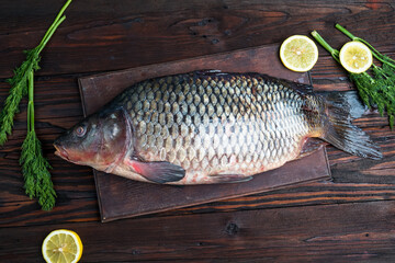 Fresh carp on a board on a dark background with lemons