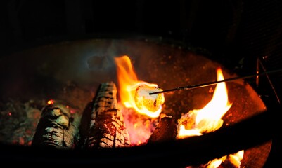 Roasting marshmallows over an open campfire.