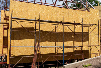 A construction site where a lightweight summer house made of a metal frame and wooden slabs is being built for outdoor recreation