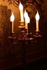A luxurious chandelier with five candles lit up in the dark
