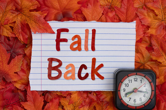Fall Back on lined paper with a clock with fall leaves for daylight savings time