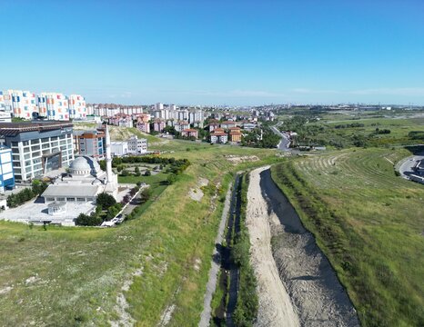 Aerial view of the stark white minaret of a mosque rising against the skyline juxtaposed with modern buildings and green spaces, Arnavutk&Atilde;&para;y, &Auml;&deg;stanbul, T&Atilde;&frac14;rkiye.