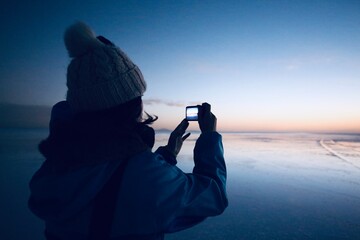 ウユニ塩湖の朝焼けを撮影する女性