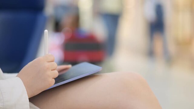 Person is writing on a tablet with a pen. The tablet is blue and the pen is white