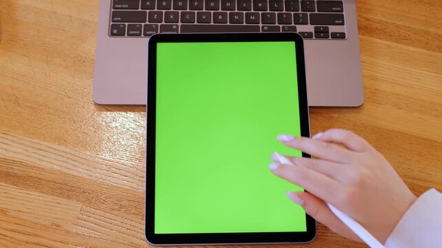 Person is pointing at a green screen on a laptop. The screen is green and has a white border