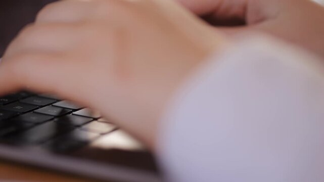 Woman is typing on a laptop. She has long fingernails. The fingernails are white