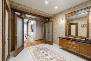 stylish entryway with wooden doors, textured walls, and a mirror above a cabinet