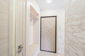 modern, bright entryway with light wood tones, a stylish door, and a built-in bench/storage area. Clean and organized