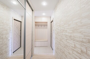 entryway with light-colored walls, a sliding door closet on the left, and a built-in storage area with coat hooks on the right. The walls have a textured pattern