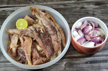 Pieces of hot smoked herring fish fillets and soft roe prepared with oil and lemon, and slices of red onions, Smoked salty Herring forage fish, salt-cured and smoked, also known as silver darlings