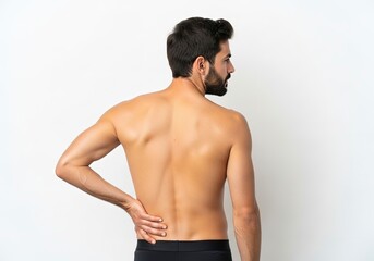 Fototapeta premium A shirtless man with a beard seen from the back holds his lower back with a hand