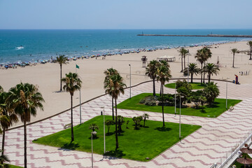 Seafront promenade with the beach full of people enjoying the sand and the sea water