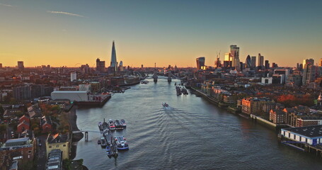 Fototapeta premium River Thames reflecting London cityscape at sunset, with The Shard and Tower Bridge standing out in the warm golden light, creating a breathtaking panorama of England's capital. Drone flight