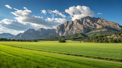 Obraz premium Green Meadow and Rugged Mountains Under Blue Sky grass