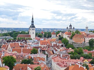 Aerial view of Tallinn Old Town, Estonia, showcasing historic medieval architecture, red rooftops, narrow cobblestone streets, and city walls. The image captures the charming and well-preserved herita