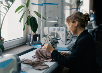 Woman sewing lingerie at a workstation with natural light