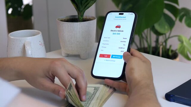  Close-up of hands transitioning from researching an electric vehicle online to preparing cash payment - smartphone shows detailed EV specs while hands hold banknotes. 