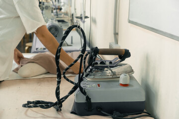 Seamstress working with fabric and steam iron in a tailor workshop