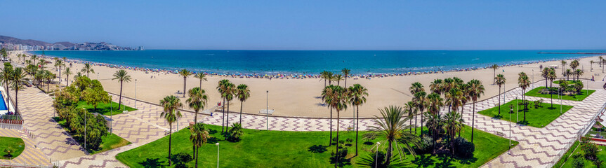 Seafront promenade with the beach full of people enjoying the sand and the sea water
