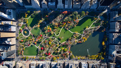 Aerial view of Central Park in Autumn vibrant foliage with surrounding skyscrapers and lake reflecting sky in New York City
