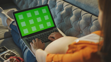 Pregnant woman using laptop with green screen and tracking markers