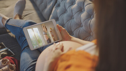 Pregnant woman watching online prenatal yoga class on tablet