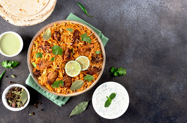 Spiced indian chicken masala biryani with chapati raita on gray background. Top view. Copy space. 