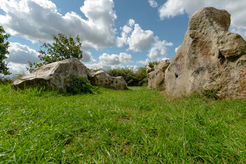 Von der Stirnseite aus zeigen sich zwei äußere Reihen der mächtigen Steine des rekonstruierten Großsteingrabs St. Anneberg. Jeder Stein trägt seine eigene Form und Struktur, eingebettet in die grüne L