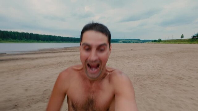 The guy is happily running along the beach, enjoying his freedom. A trained man runs through the sand, emotionally rejoicing in this process. From the first person.