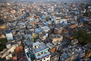 Aerial view of densely packed buildings and structures with varying heights under the soft morning light, creating a maze-like urban landscape, Varanasi, Uttar Pradesh, India.