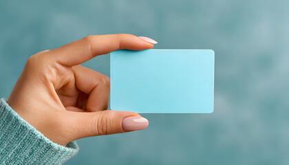 Close-up of hand holding blank light blue credit card against soft pastel background. Modern payment method for purchases and transactions, showcasing digital banking and contactless technology.