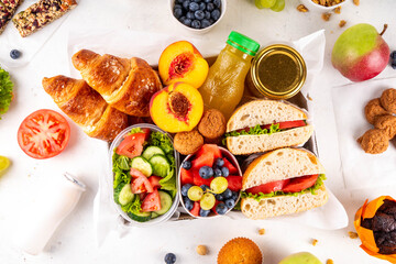 Preparation or ready made brunch box with sandwiches, salad, croissant, cookie and fruit for dessert, berries, juice or smoothie. Quick lunch break, time saving catering delivered healthy meal 