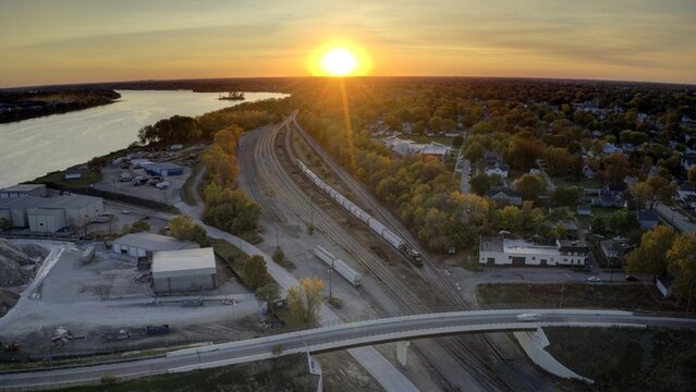 Aerial view of train tracks stretching through the landscape as the sun sets over the Maumee River, Toledo, Ohio, United States.
