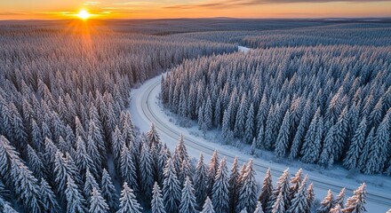 Aerial view of a snow covered forest road at sunset
